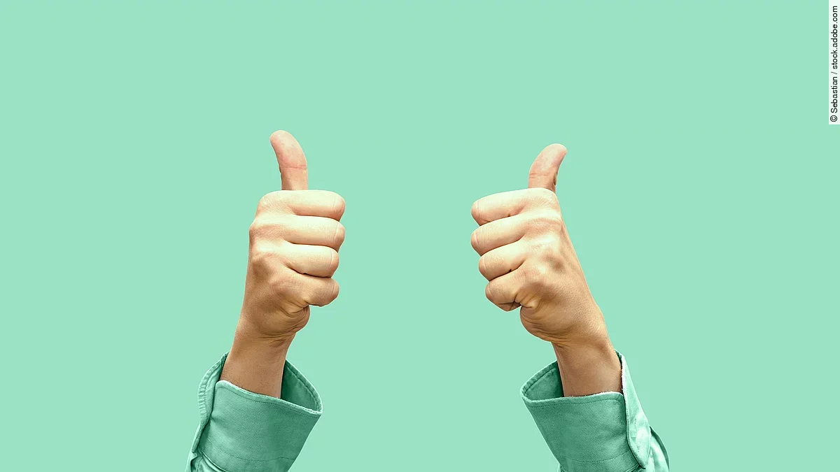 Daumen hoch Vor türkisem Hintergrund zeigen zwei Hände Daumen nach oben.