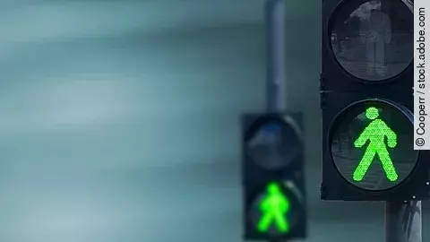 Zwei Fußgängerampeln hintereinander, die beide auf grüne Ampelmännchen geschalten sind.