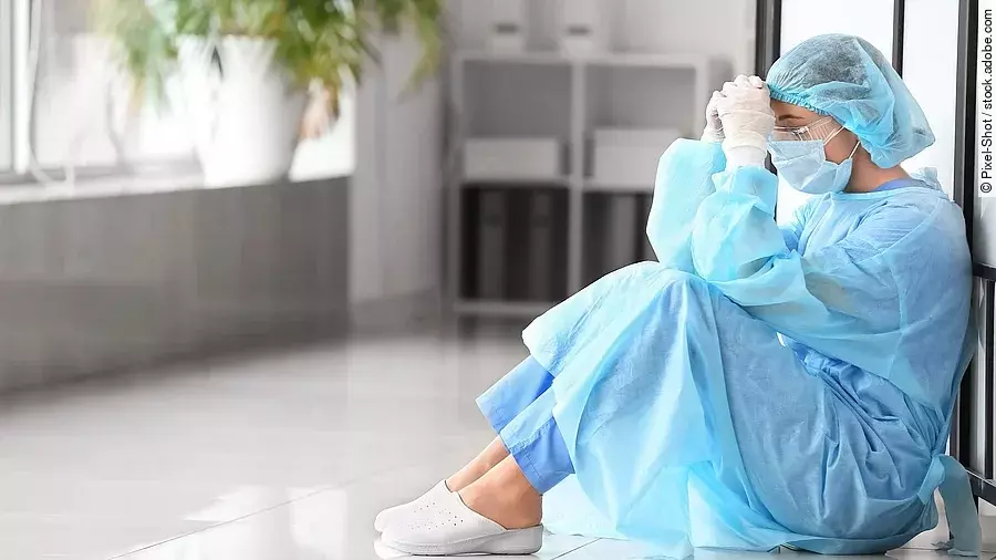 Belastetes medizinisches Personal Belastetes medizinisches Personal sitzt am Boden eines Krankenhausflures.
