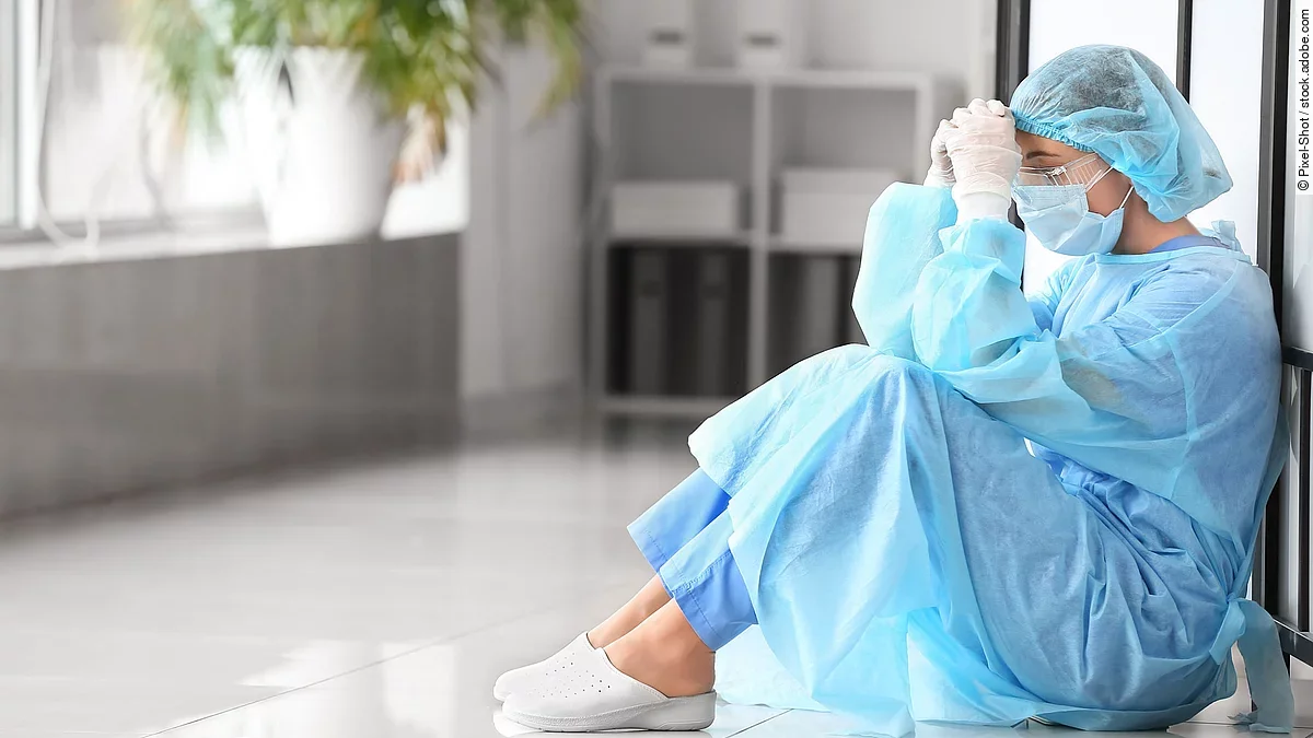 Belastetes medizinisches Personal Belastetes medizinisches Personal sitzt am Boden eines Krankenhausflures.