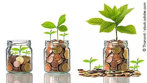 Fünf Gläser stehen nebeneinander. Das linke ist leer, das rechte gänzlich mit Münzen gefüllt. Dazwischen steigt die Menge der Münzen. Aus den Münzen wächst eine Pflanze, die mit zunehmender Geldsumme immer größer wird.