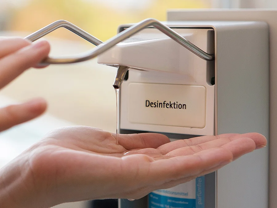 Eine Person benutzt einen Desinfektionsspender mit der Hand.