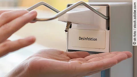 Eine Person benutzt einen Desinfektionsspender mit der Hand.