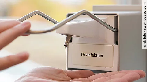 Eine Person benutzt einen Desinfektionsspender mit der Hand.