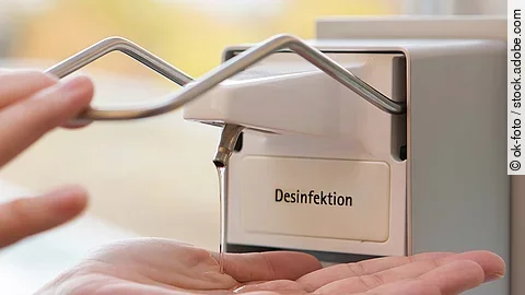 Eine Person benutzt einen Desinfektionsspender mit der Hand.