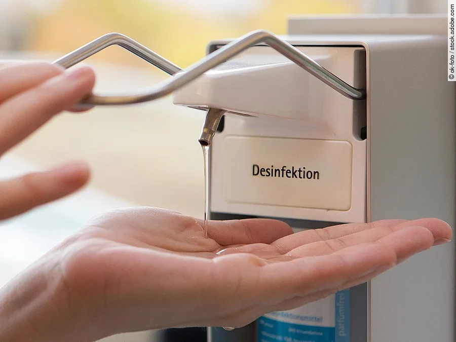 Eine Person benutzt einen Desinfektionsspender mit der Hand.