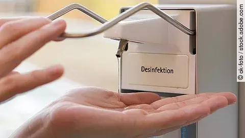 Eine Person benutzt einen Desinfektionsspender mit der Hand.