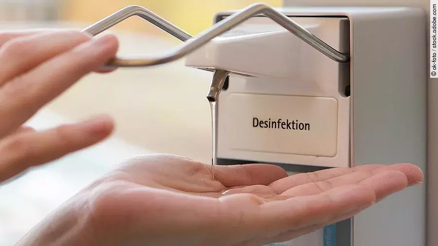 Eine Person benutzt einen Desinfektionsspender mit der Hand.