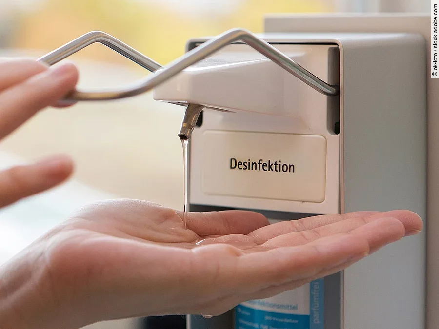 Eine Person benutzt einen Desinfektionsspender mit der Hand.