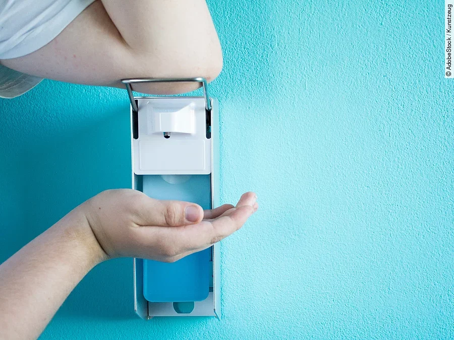 Desinfektion Eine Person betätigt einen Desinfektionsspender mit dem Ellenbogen.
