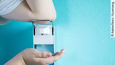 Desinfektion Eine Person betätigt einen Desinfektionsspender mit dem Ellenbogen.