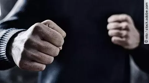 Person nimmt eine Abwehrhaltung mit geballten Fäusten ein