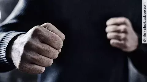 Person nimmt eine Abwehrhaltung mit geballten Fäusten ein