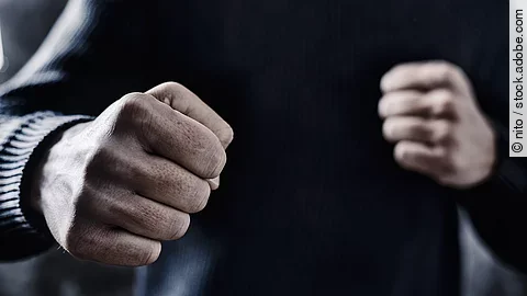 Person nimmt eine Abwehrhaltung mit geballten Fäusten ein