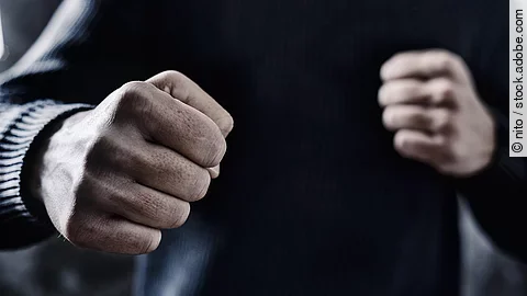 Person nimmt eine Abwehrhaltung mit geballten Fäusten ein